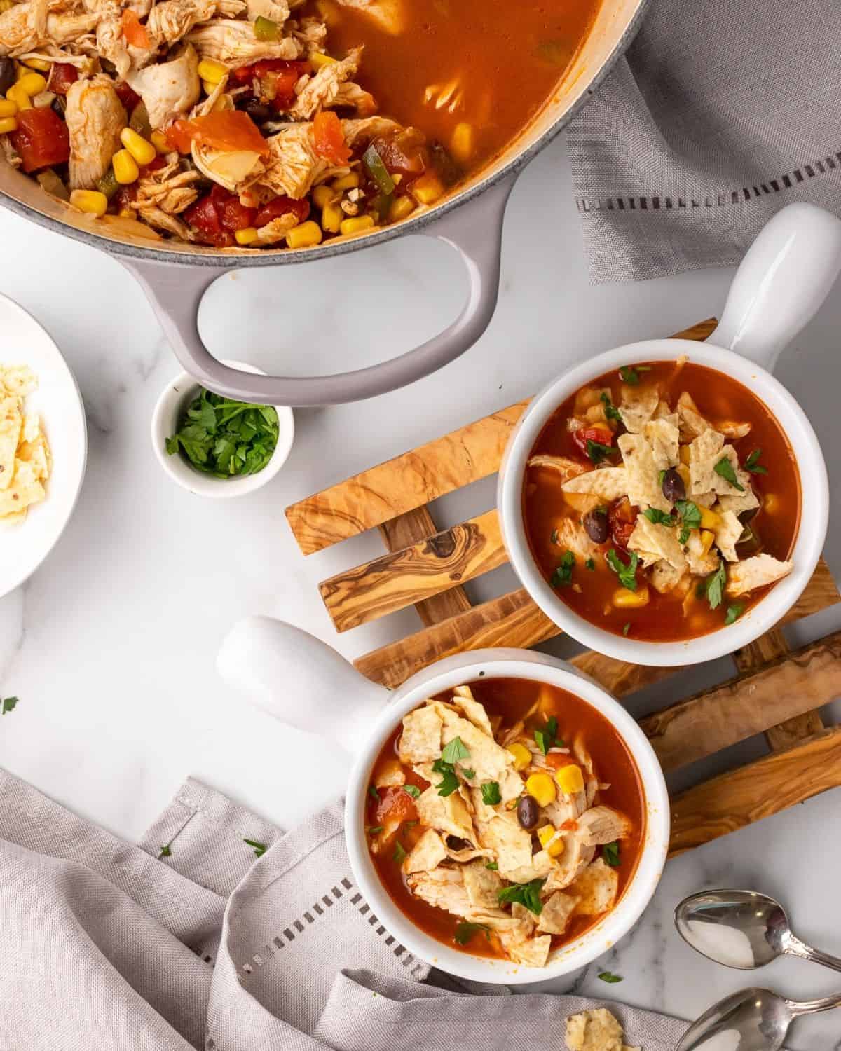 two bowls of chicken tortilla soup next to the soup pot