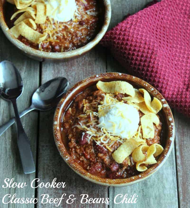 Slow Cooker Classic Beef and Beans Chili in 2 bowls, topped with sour cream, cheese and fritos.