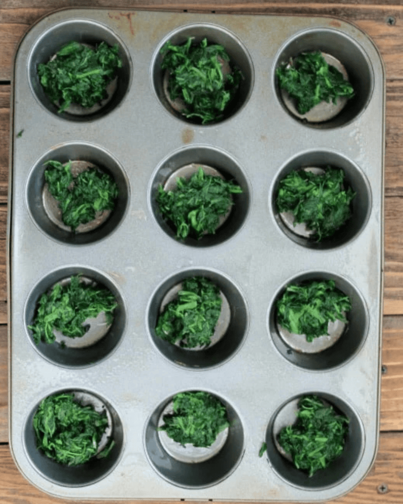 spinach in a sprayed muffin pan.