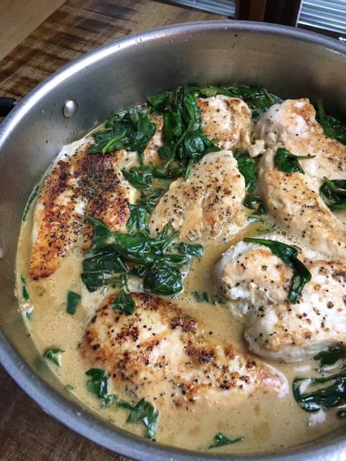 chicken and spinach in a skillet with a cream sauce