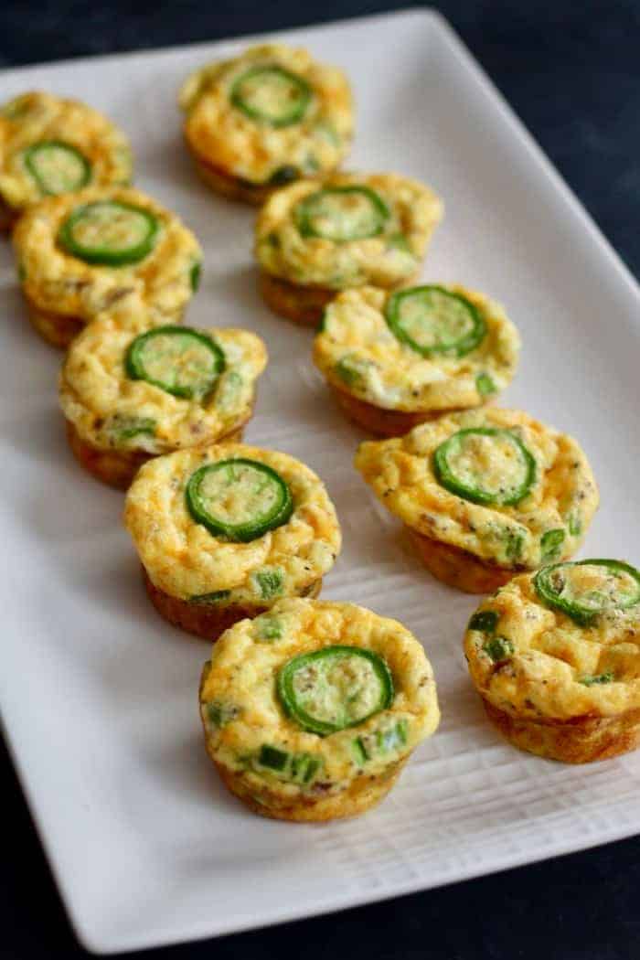 Baked low carb egg bites with cheddar, jalapeno and bacon lined on a white serving dish. 