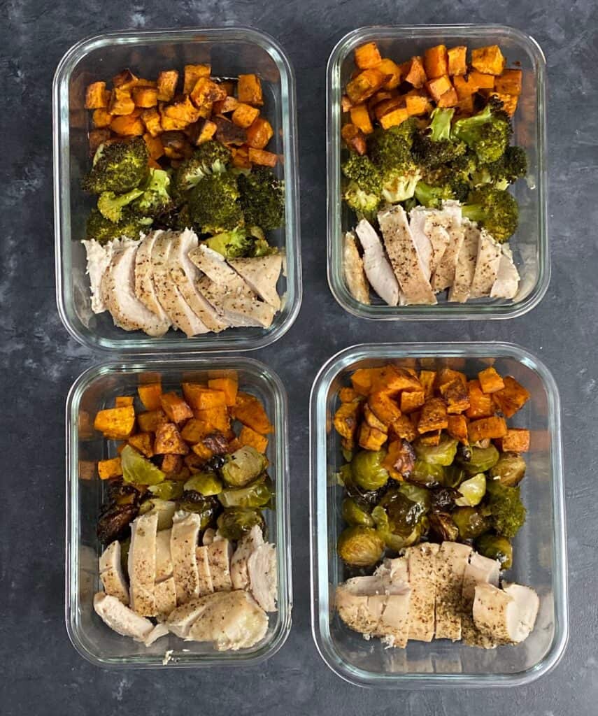 4 meal prep bowls in glass containers with chicken, broccoli, and sweet potato.