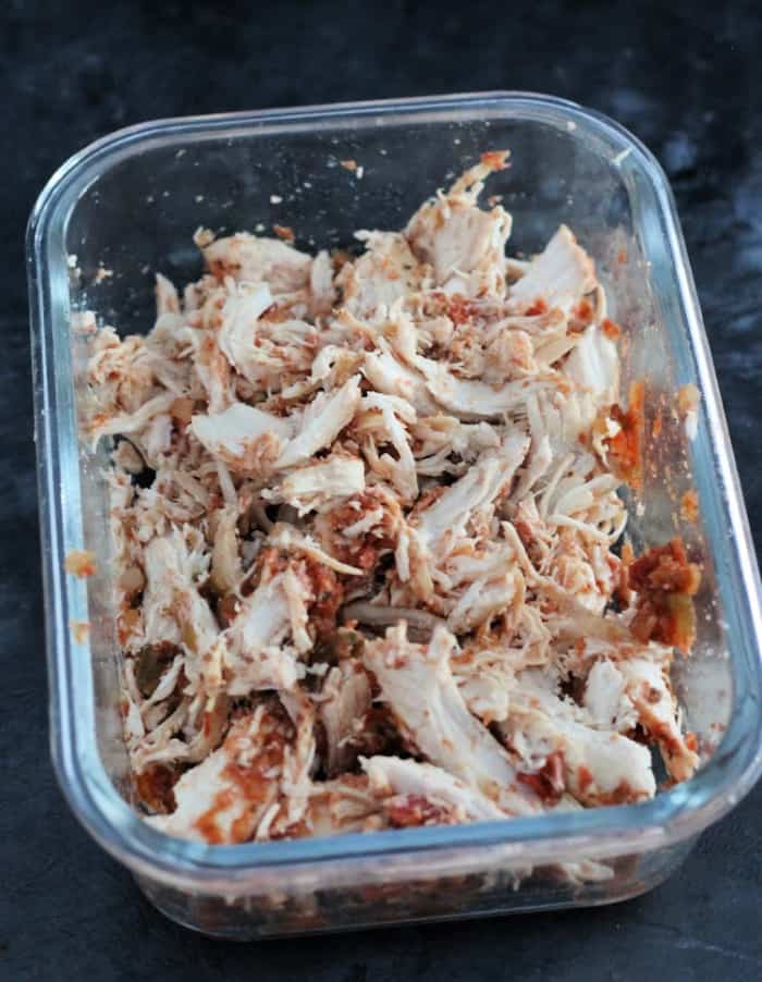 Glass container of shredded chicken made for a chicken quesadilla recipe.