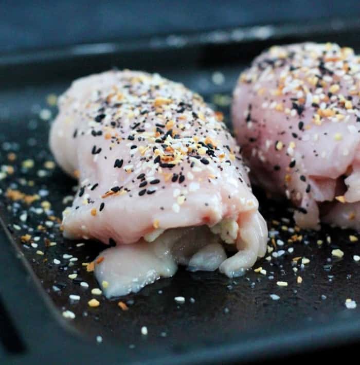 Cream cheese chicken topped with Everything But The Bagel seasoning on a baking sheet.