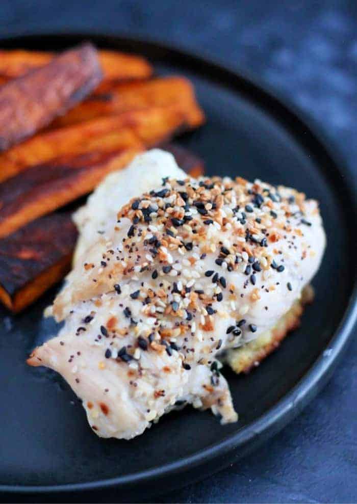 Baked cream cheese chicken with sweet potato fries on a dark plate.