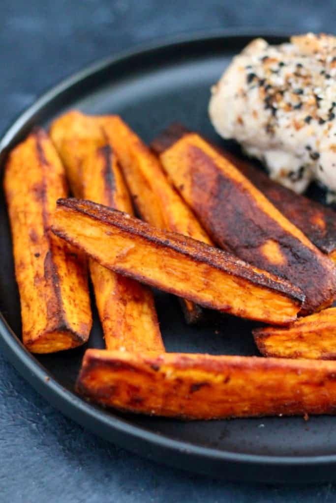Whole30 compliant crispy roasted sweet potato wedges with a chili spice seasoning on a plate.