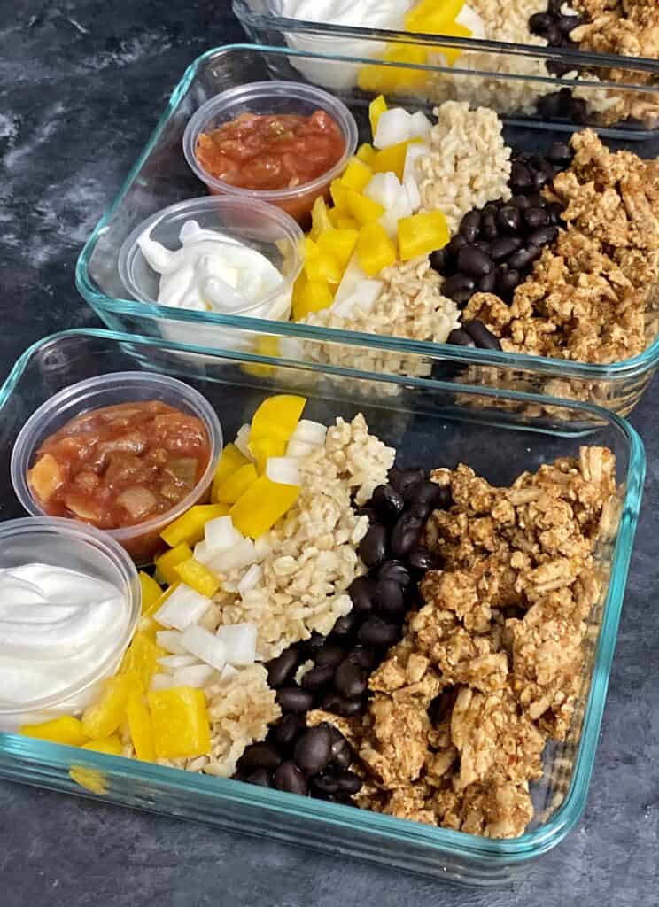 Taco meal prep bowl with ground beef, black beans, brown rice, mango, salsa and sour cream.