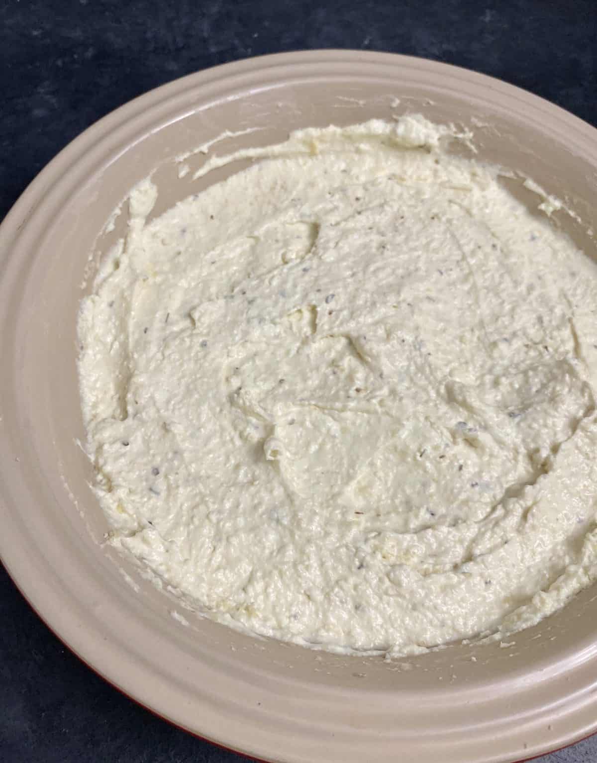 Melted cream cheese in a baking dish as base for pizza dip.