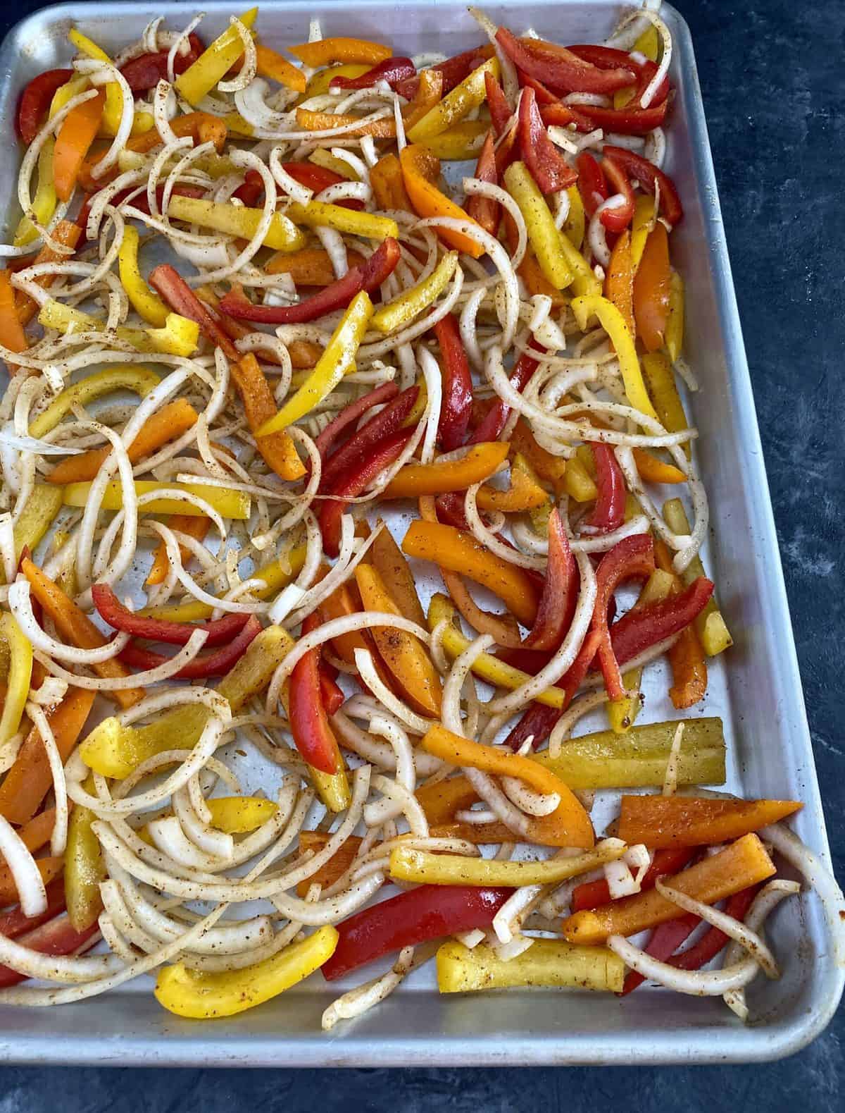 Chopped onions and colorful peppers on a sheet pan.
