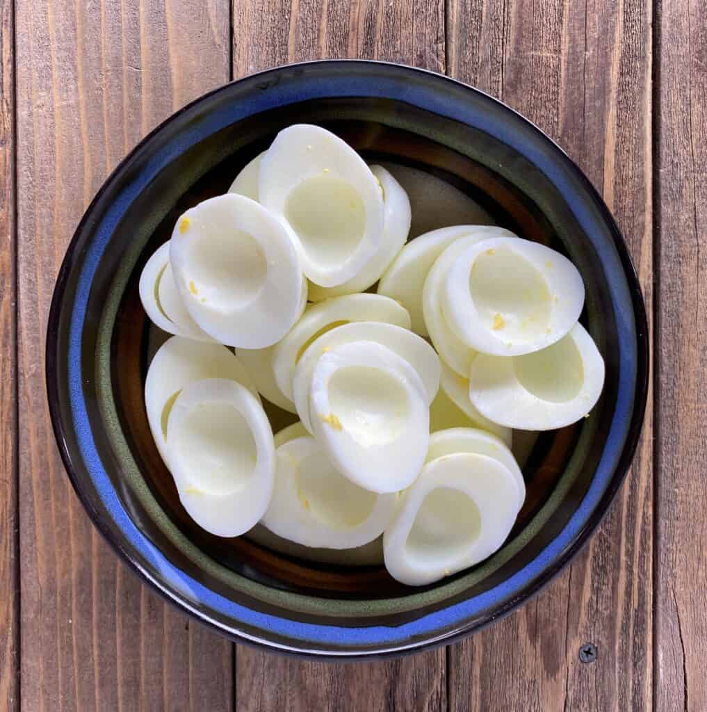 Halved eggs in a bowl prior to being filled with horseradish filling to make deviled eggs.