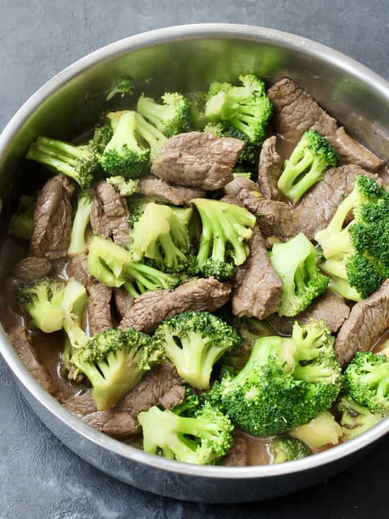 Easy Beef and broccoli stir fry in a metal bowl sitting on a dark countertop.