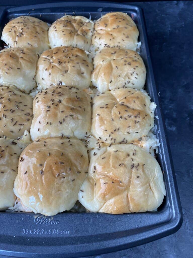 Reuben sliders packed together in a baking dish