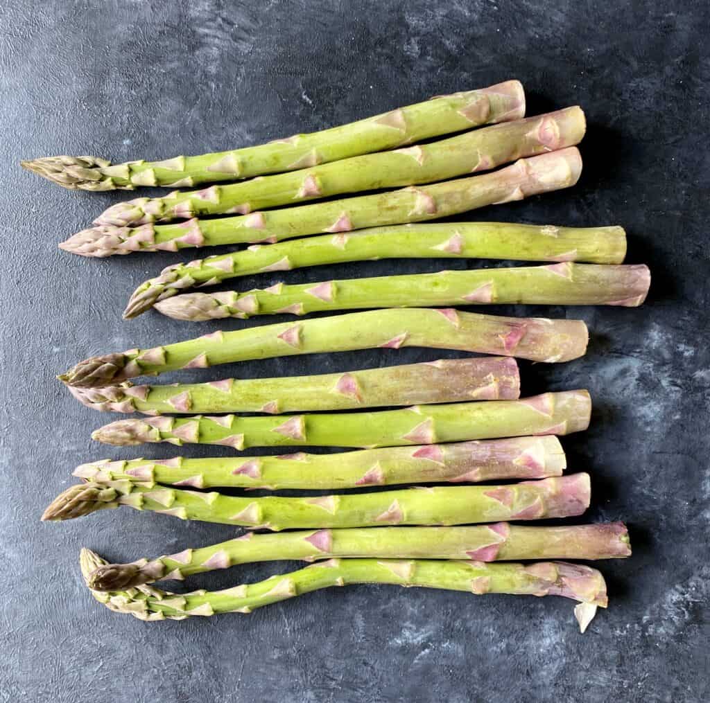 raw asparagus on dark gray table