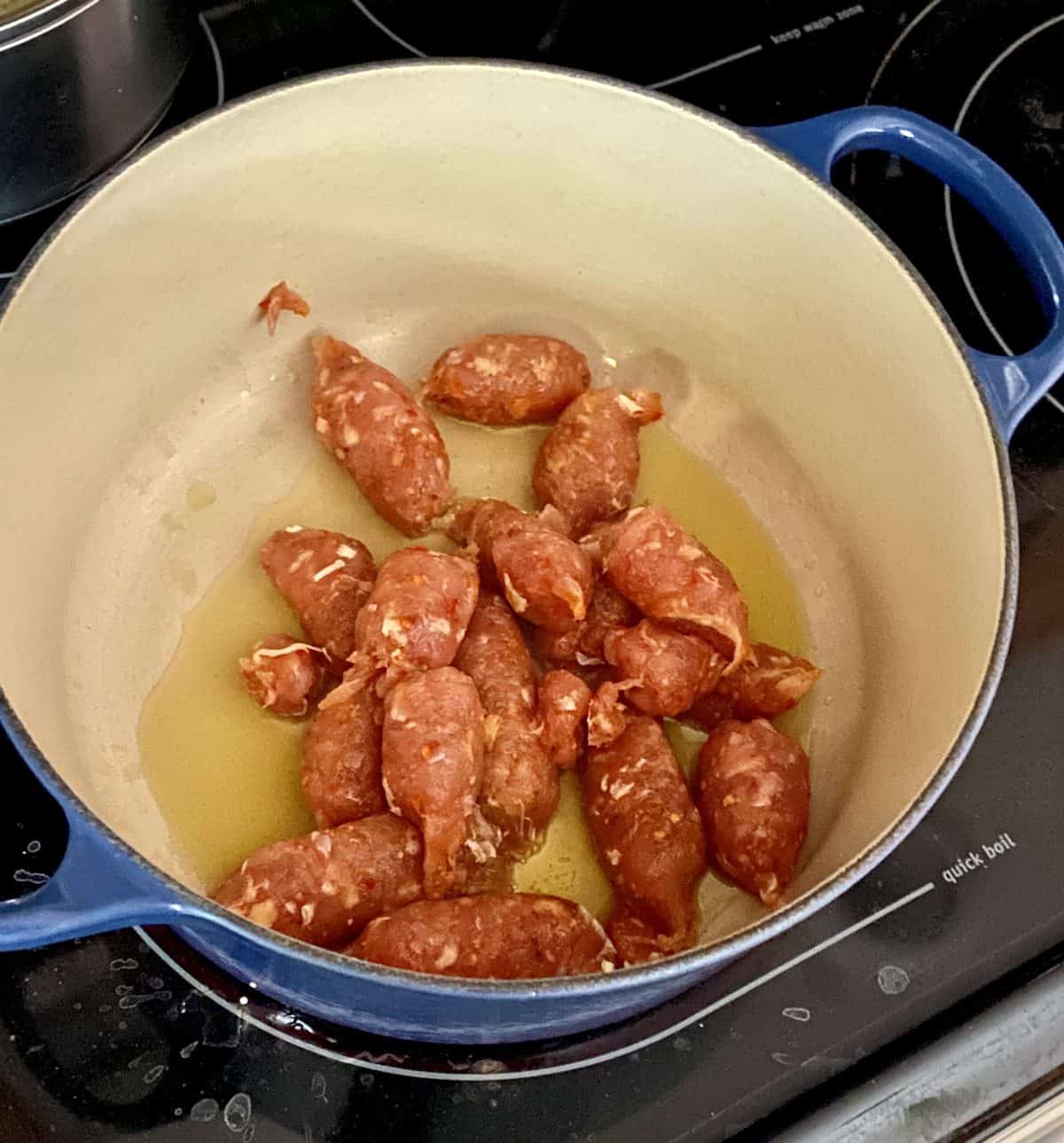 sausage link being cooked in a blue pan