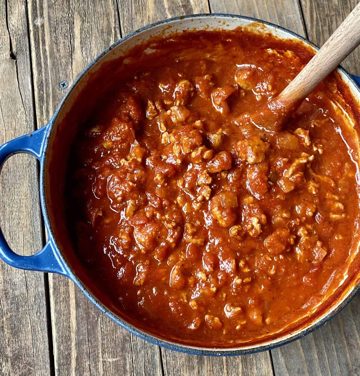 Turkey bolognese sauce in a blue pot on a wooden table