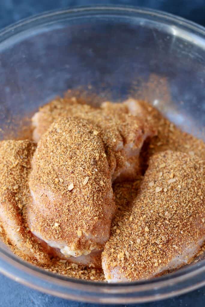raw chicken covered with seasoning in a bowl