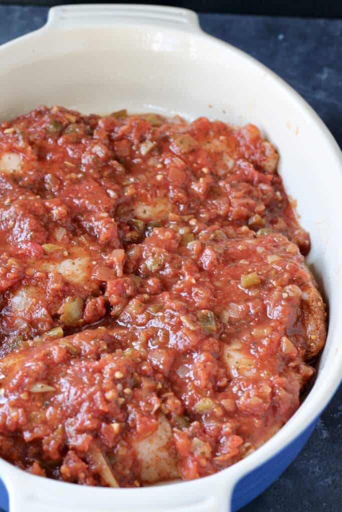 Raw chicken and salsa in a baking dish