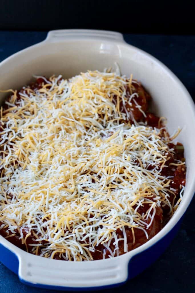 Salsa and chicken covered with shredded cheese before baking