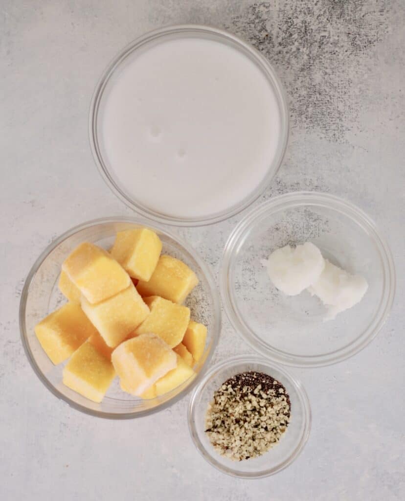 Ingredients for a mango smoothie in separate bowls.