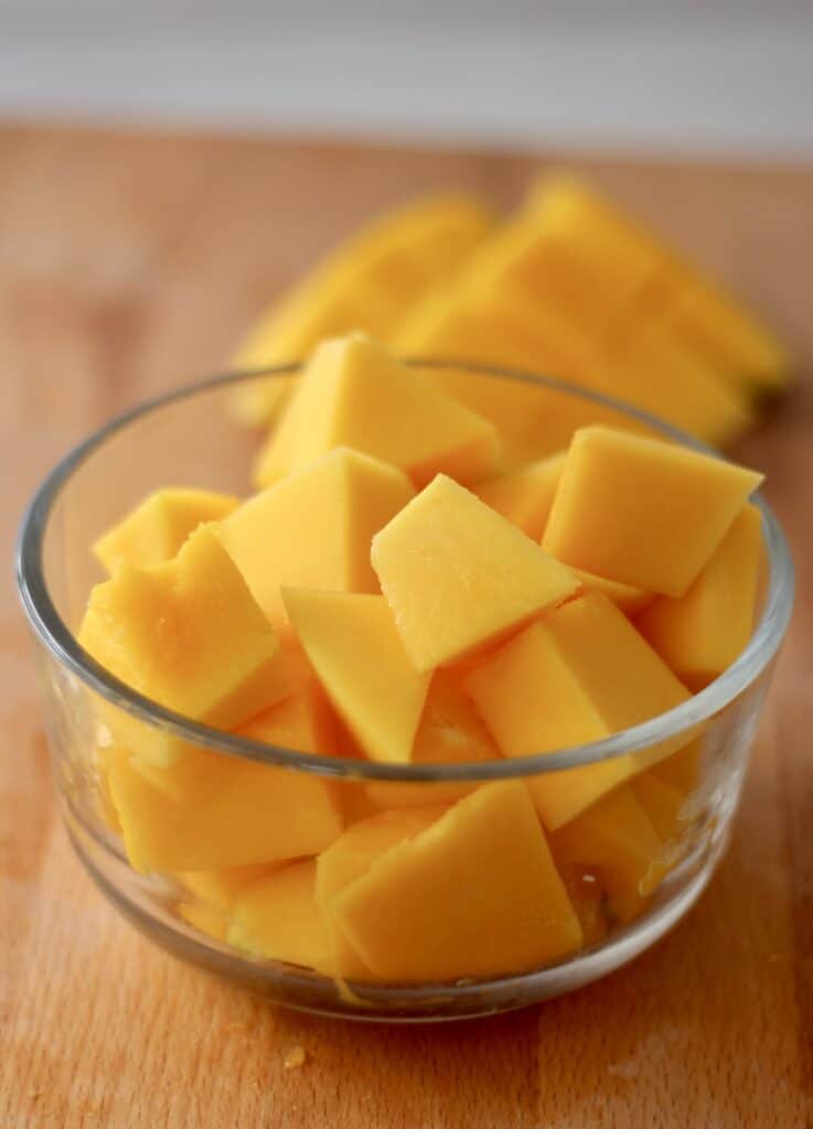 Chunks of freshly cut mango in a glass bowl.