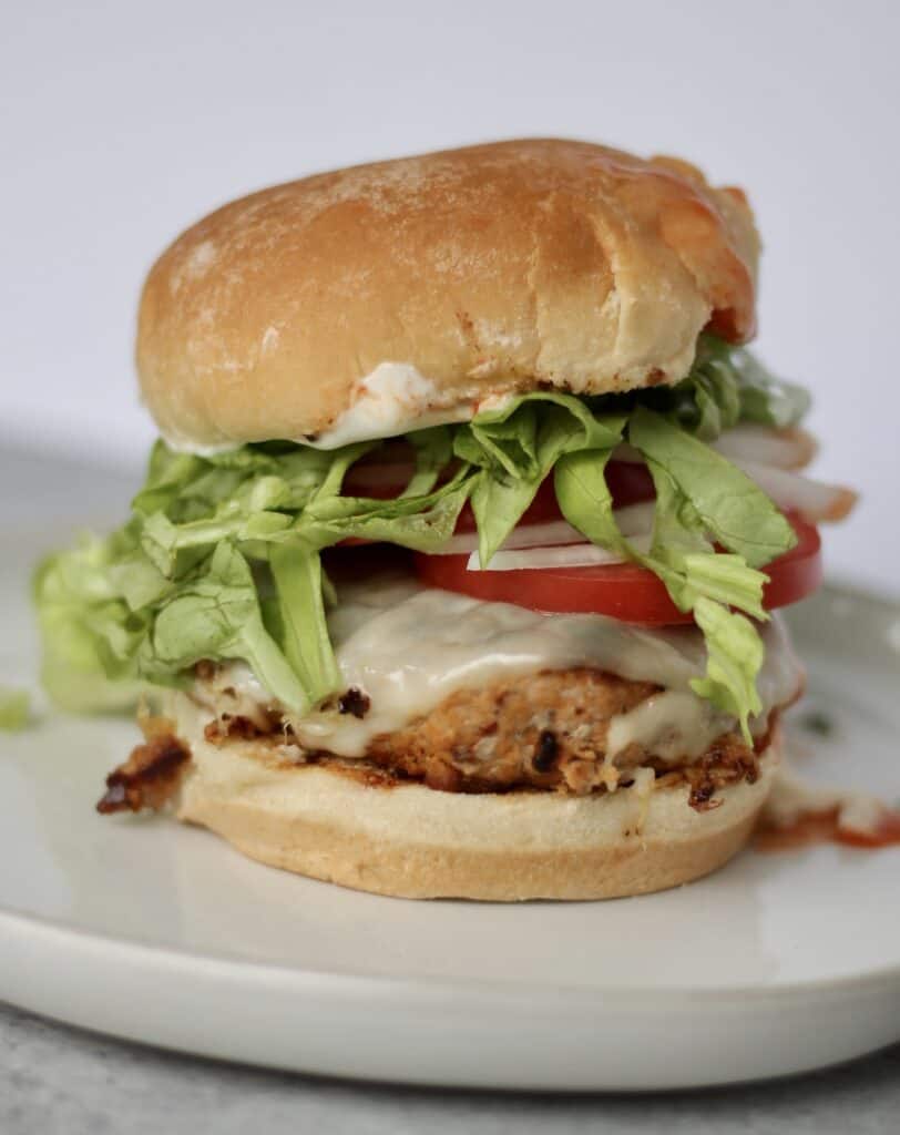 Blue cheese buffalo turkey burger piled with tomato, lettuce, and cheese.