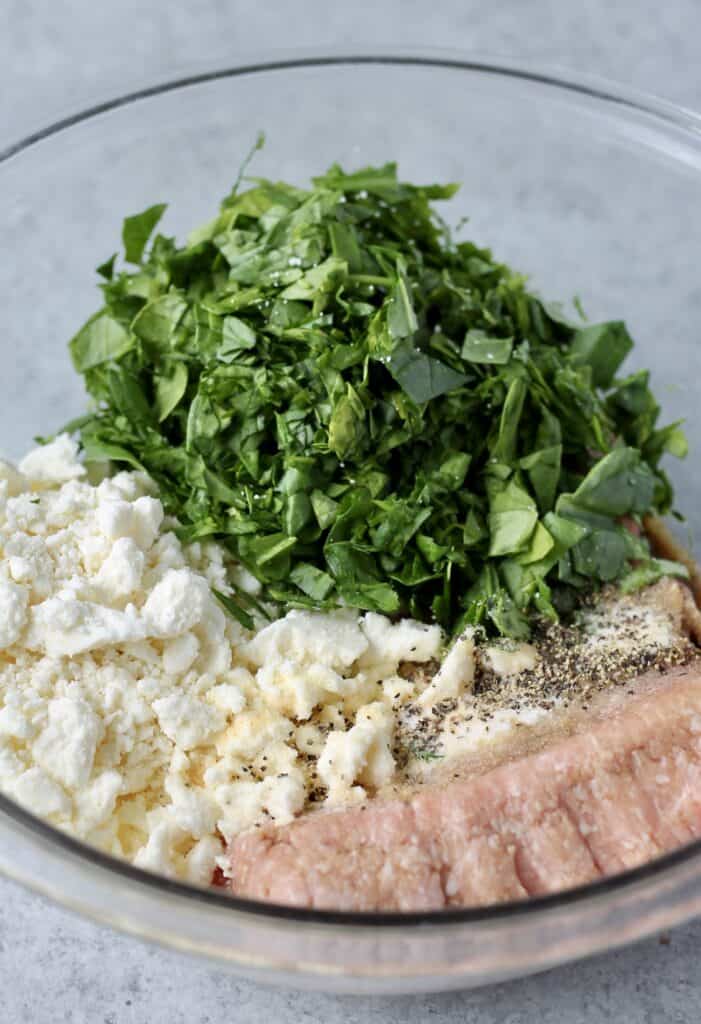 Greek turkey burger ingredients in a bowl - ground turkey, feta, spinach