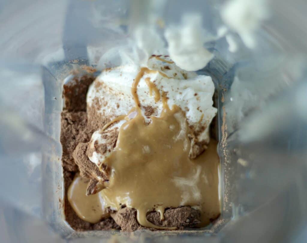 Aerial view of a blender filled with yogurt, peanut butter, and cocoa for a smoothie