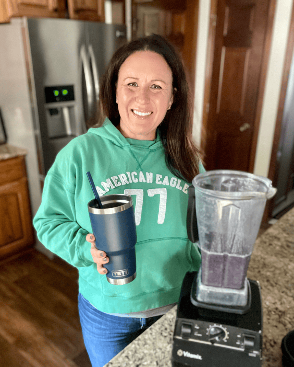 Tammy standing with a smoothie next to her vitamix blender.