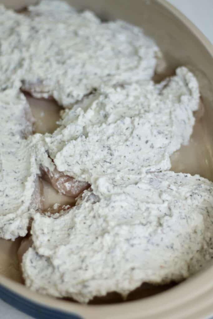 greek yogurt mixture on chicken breast in baking dish