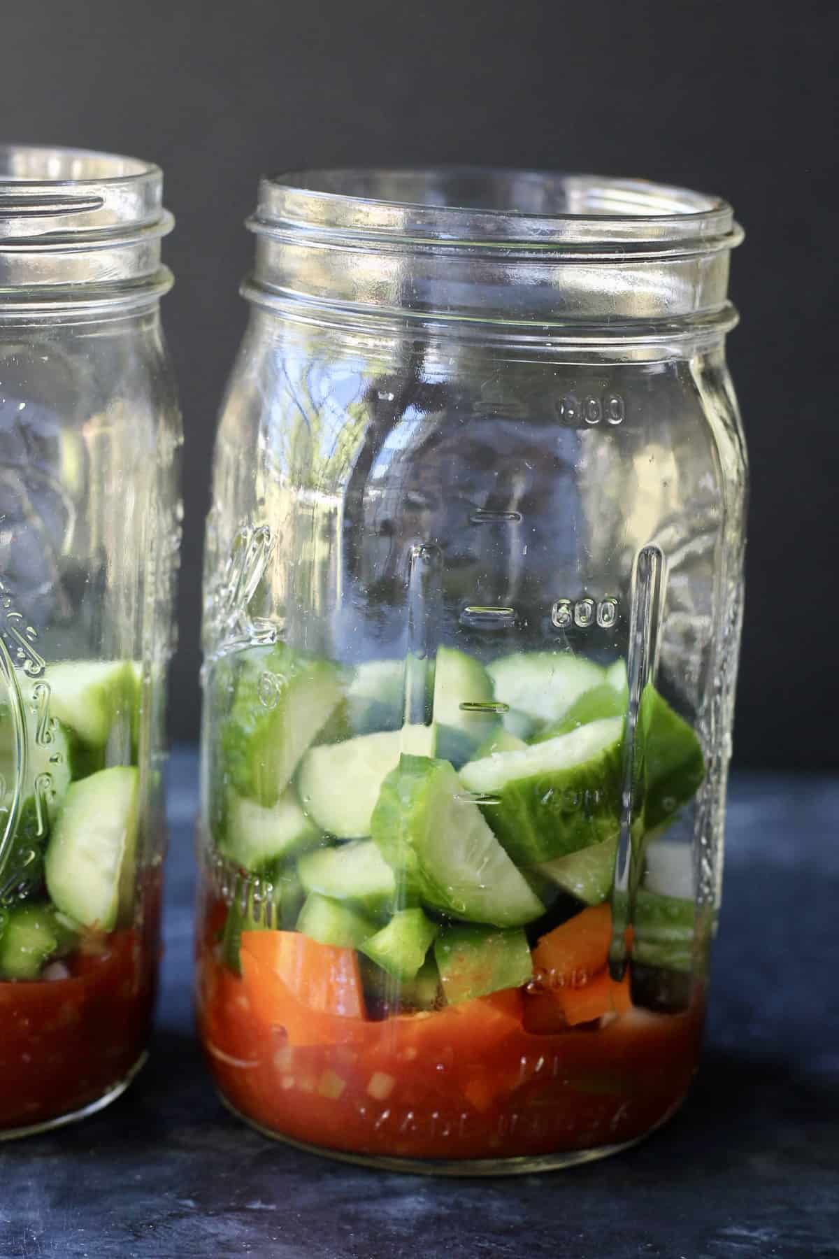 adding cucumbers to mason jar salad 