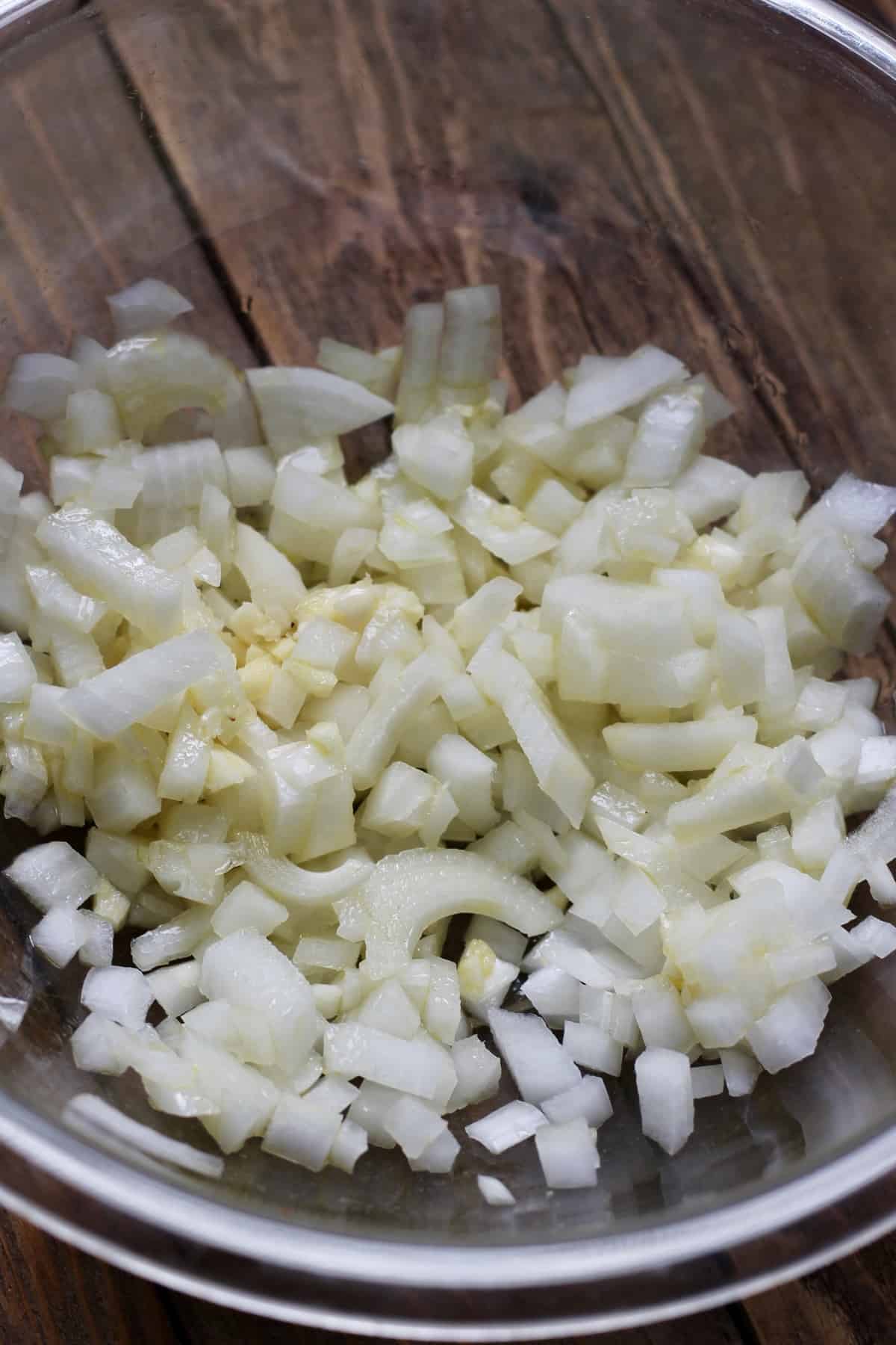 chopped onions and garlic in a glass bowl 