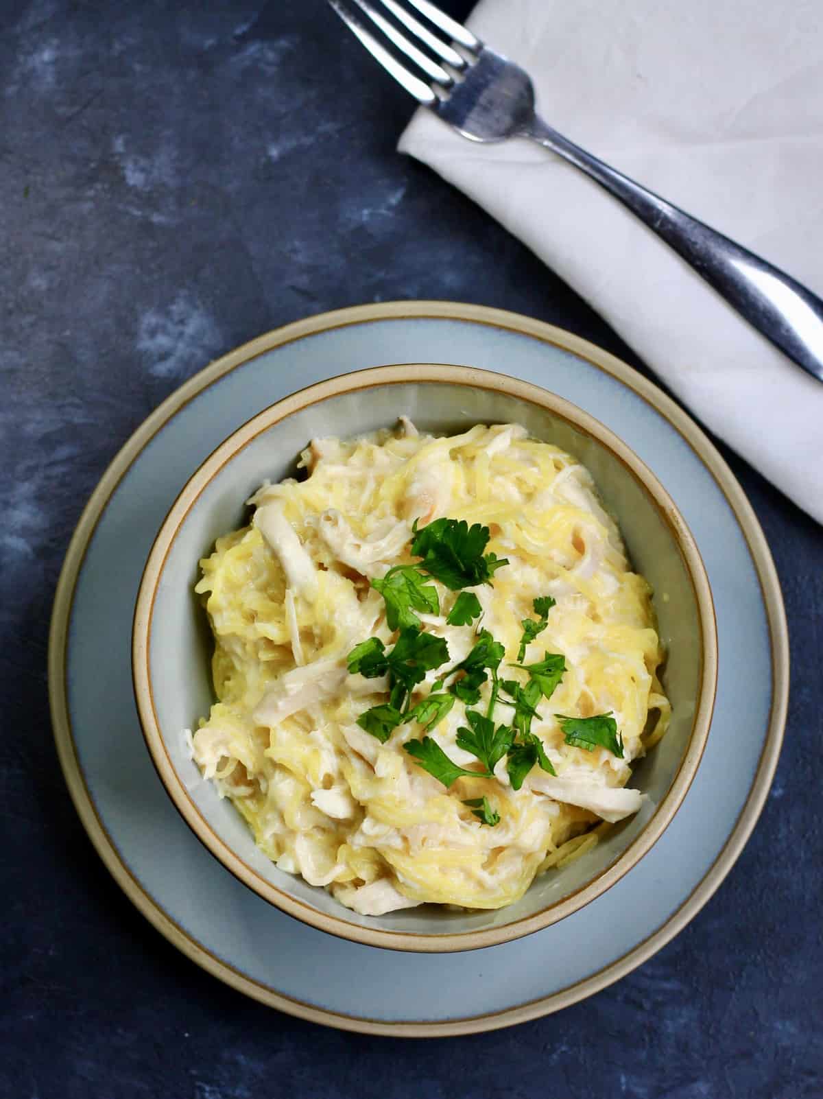 Spaghetti squash alfred in a blue bowl and topped with parsley