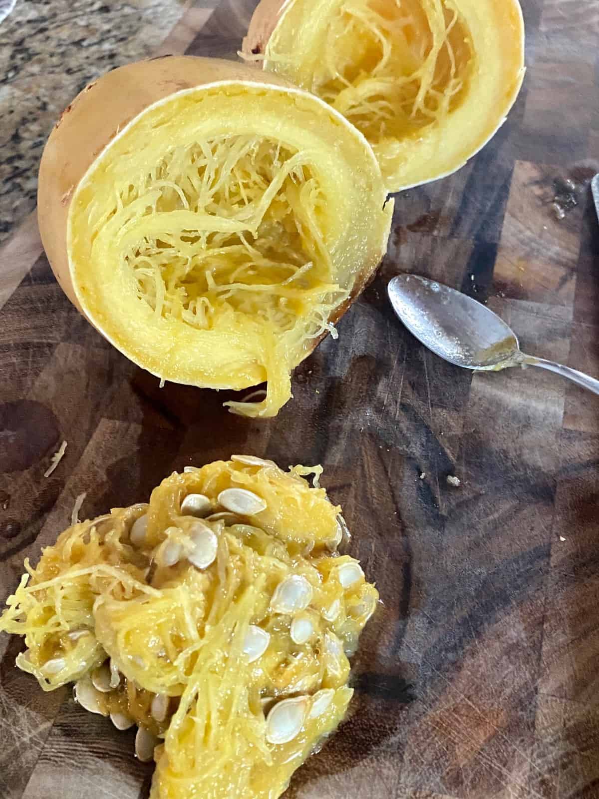 scooping out seeds from a cooked spaghetti squash with a spoon. 