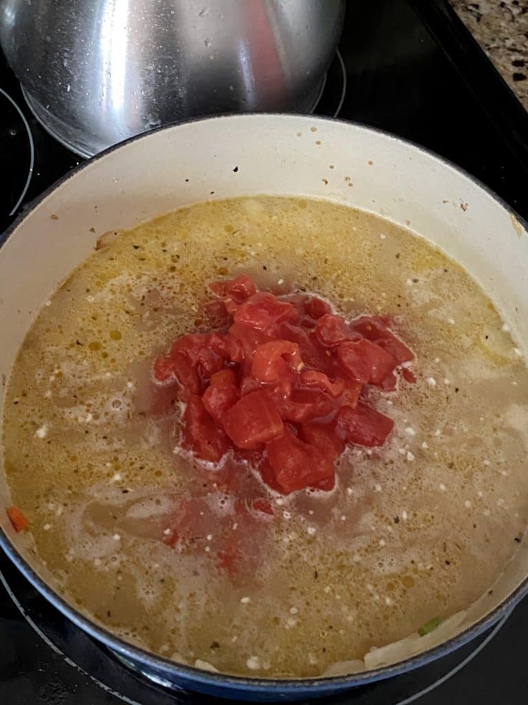 chicken stock and canned tomatoes are put into the soup pot