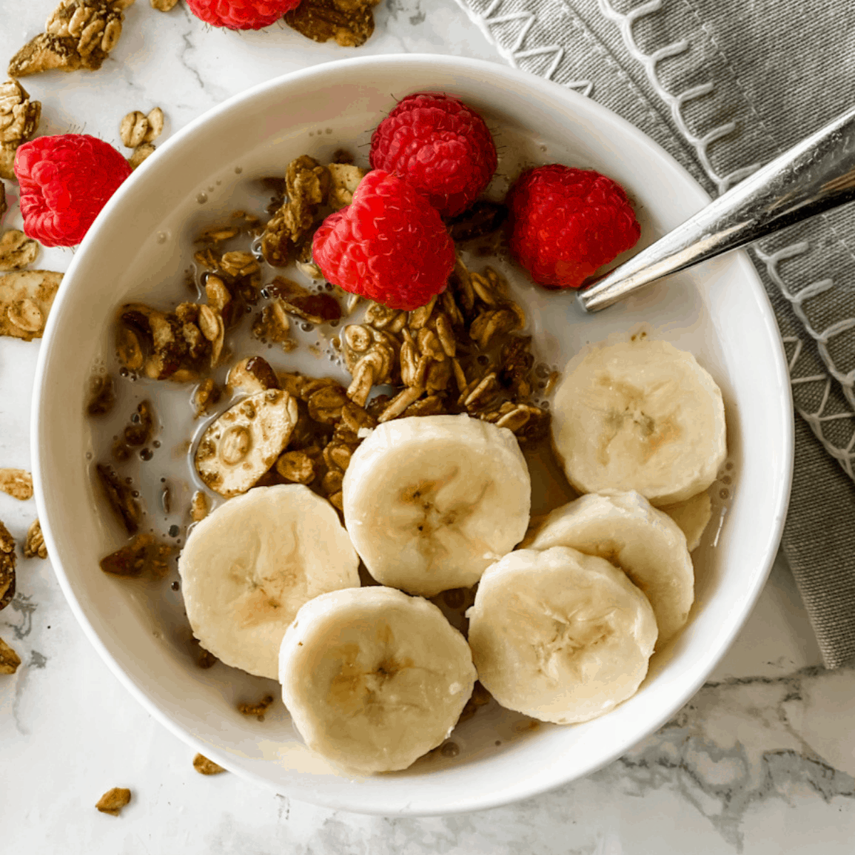 granola in a bowl with milk and bananas