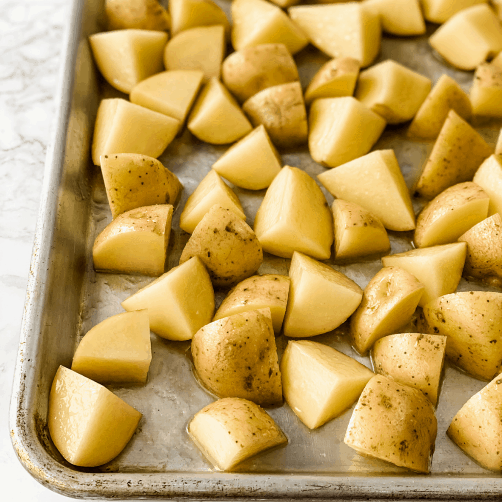 raw potatoes cut into chunks on a baking sheet