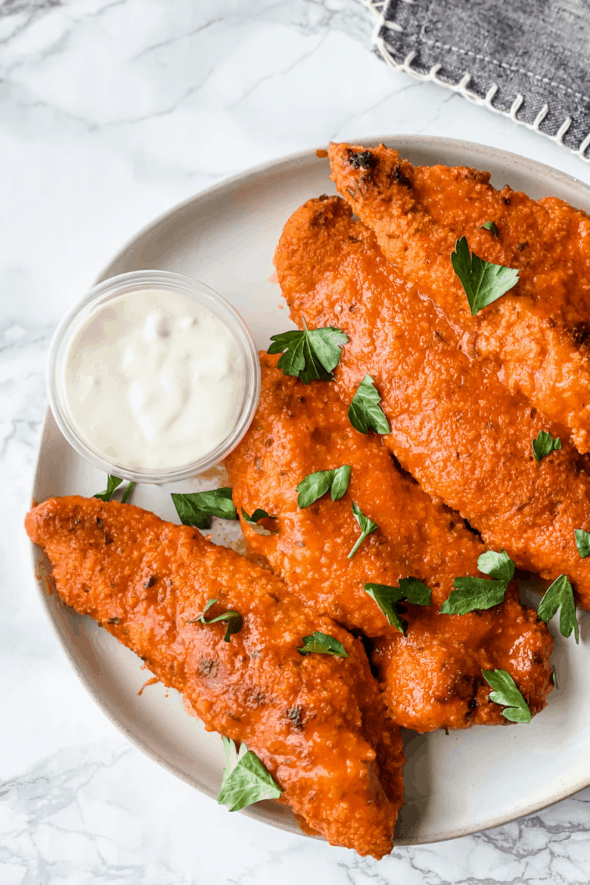 Baked chicken in hot sauce on a plate with a side of blue cheese.