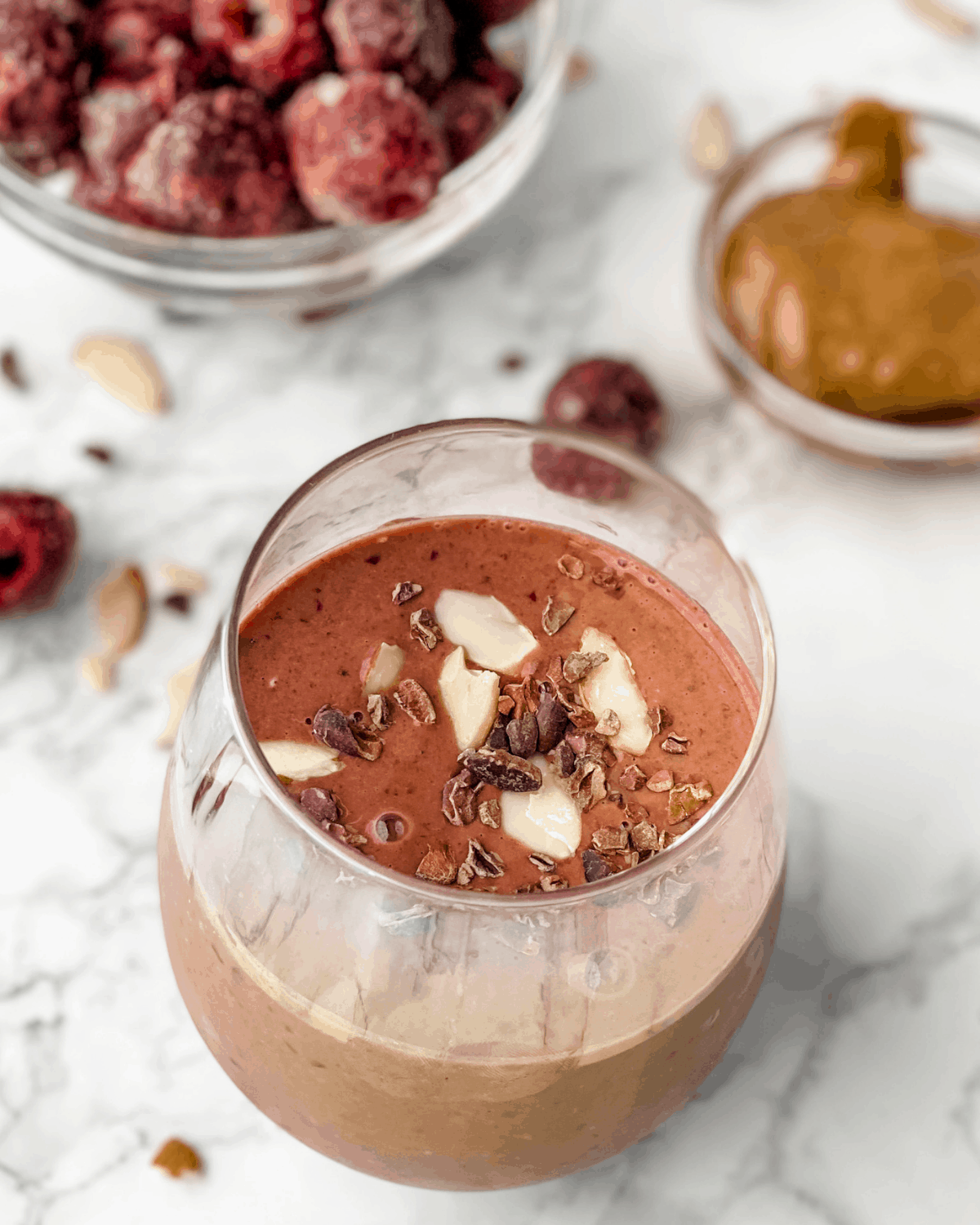 chocolate cherry smoothie with frozen cherries and almond butter in the background