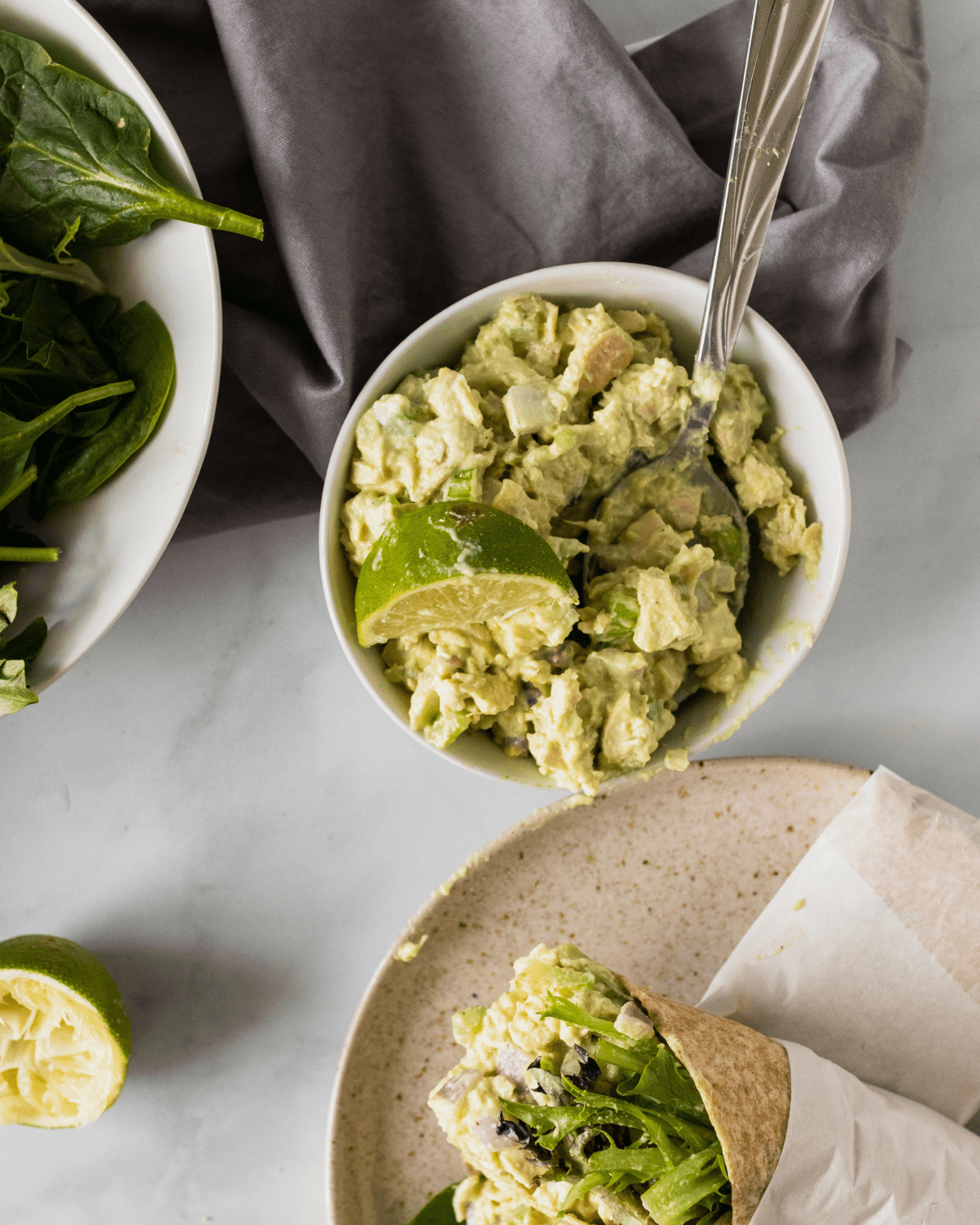 a bowl of no mayo chicken salad next to a chicken salad wrap.