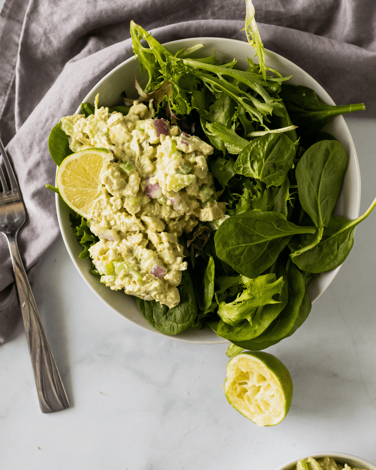 chicken salad on a bed of greens with a slice of lime