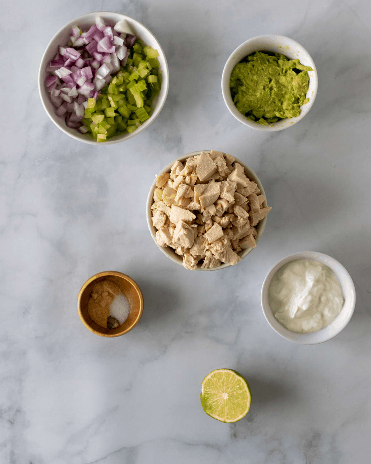 Ingredients for no mayo chicken salad. Chopped chicken, Greek yogurt, avocado, seasoning, and lime.