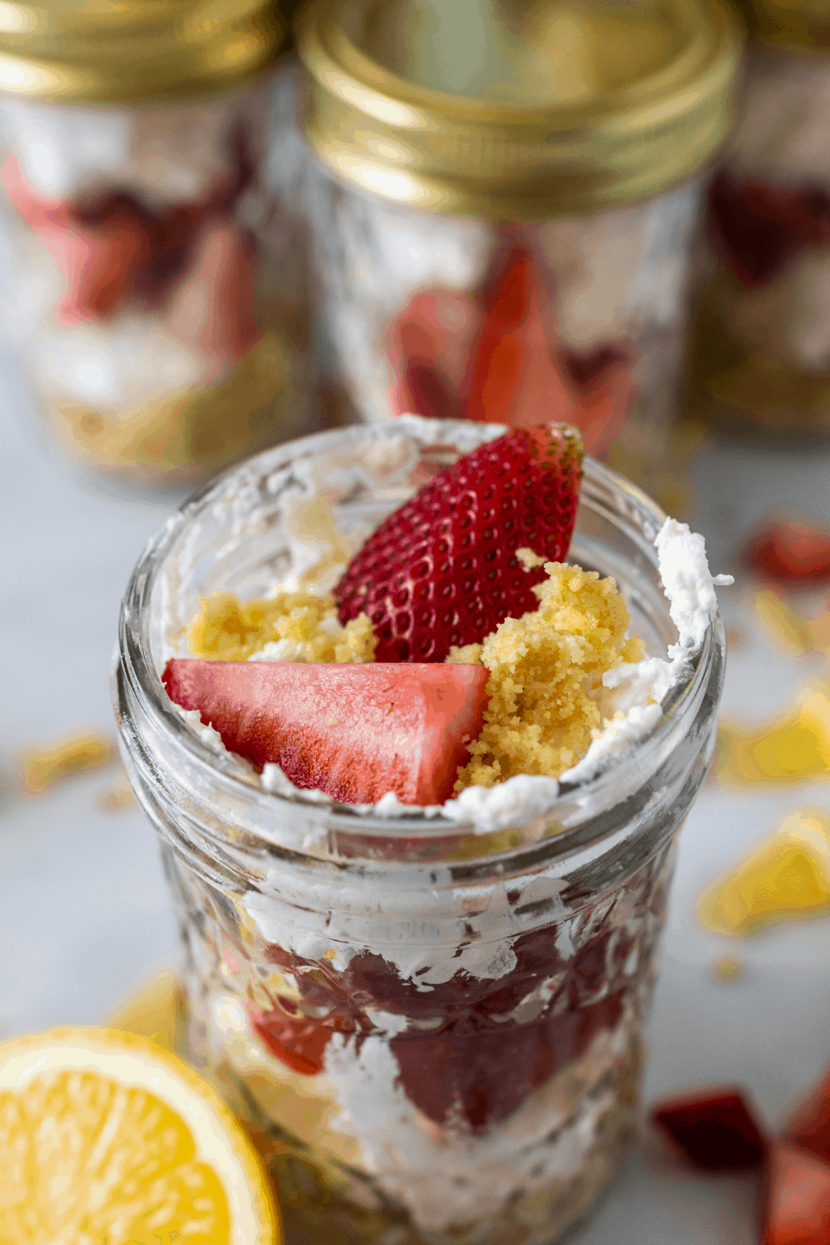 No-bake strawberry cheesecake jars with lemons next to it and more jars behind it.