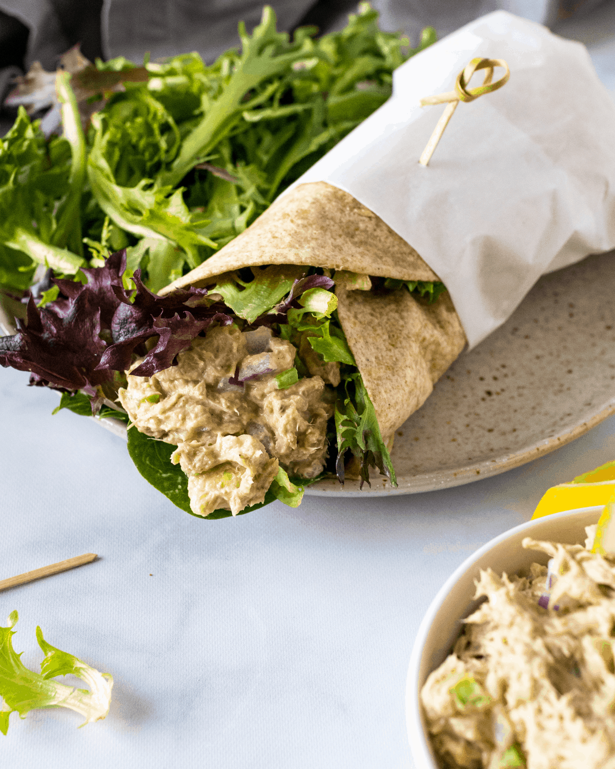 no mayo tuna salad in a wheat wrap on a plate with greens.