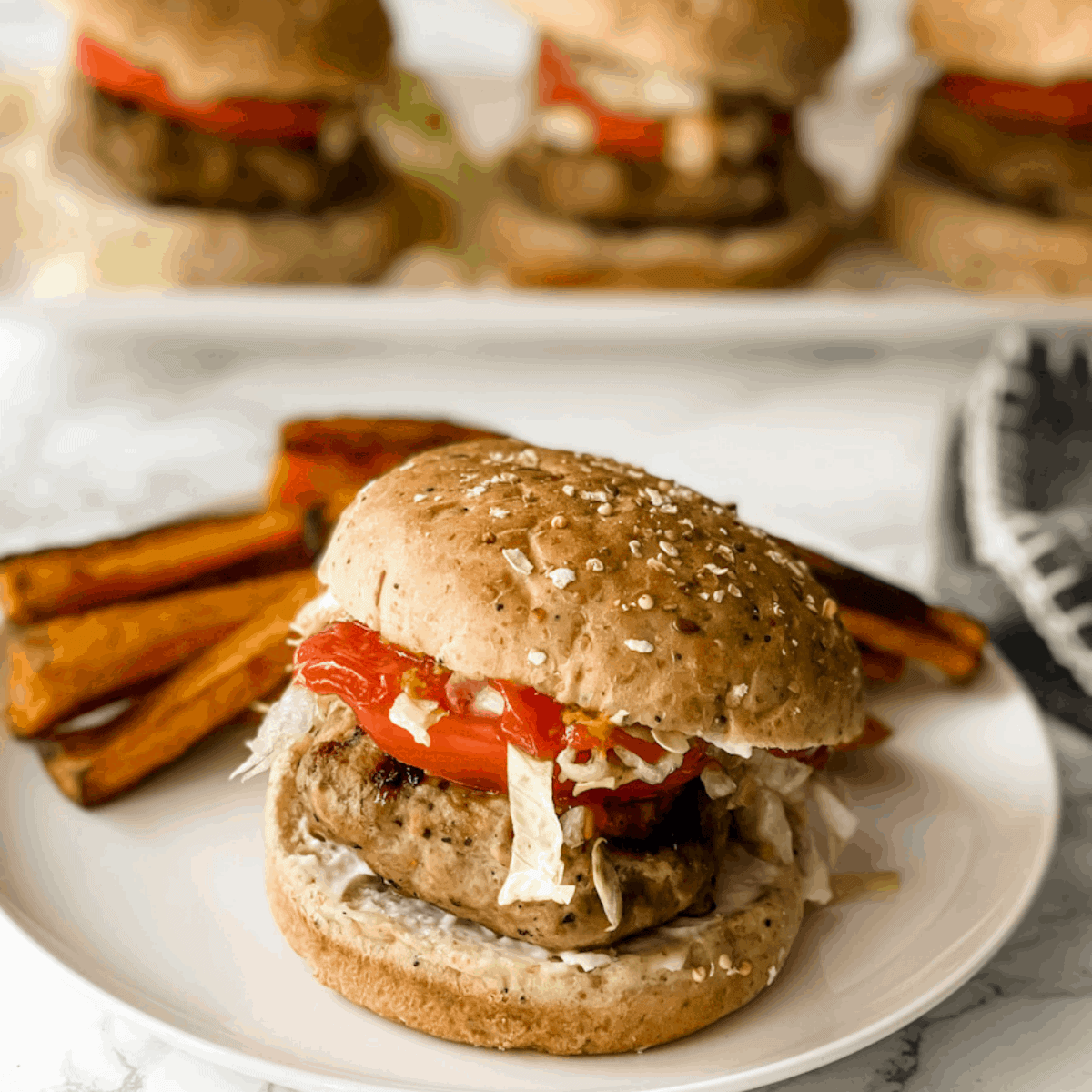 turkey burgers on a plate in the front and 3 on a platter in back