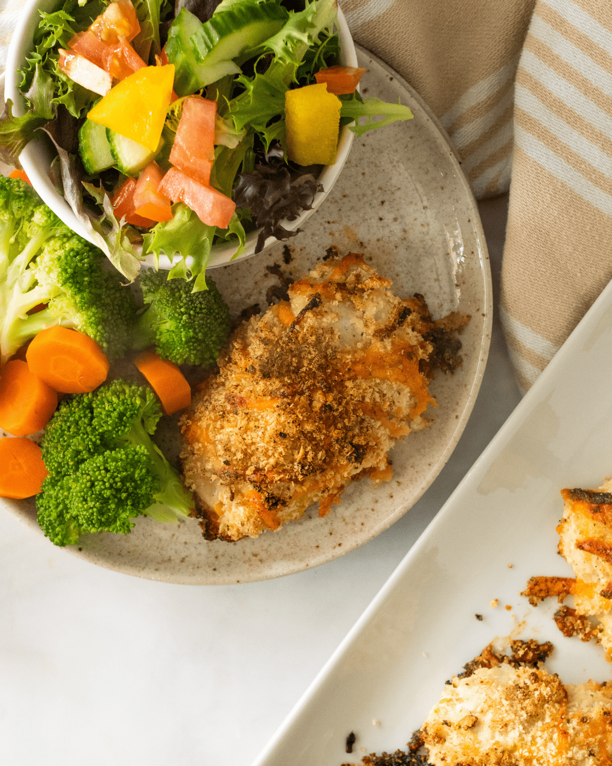 baked ranch chicken in a plate with broccoli and carrots.