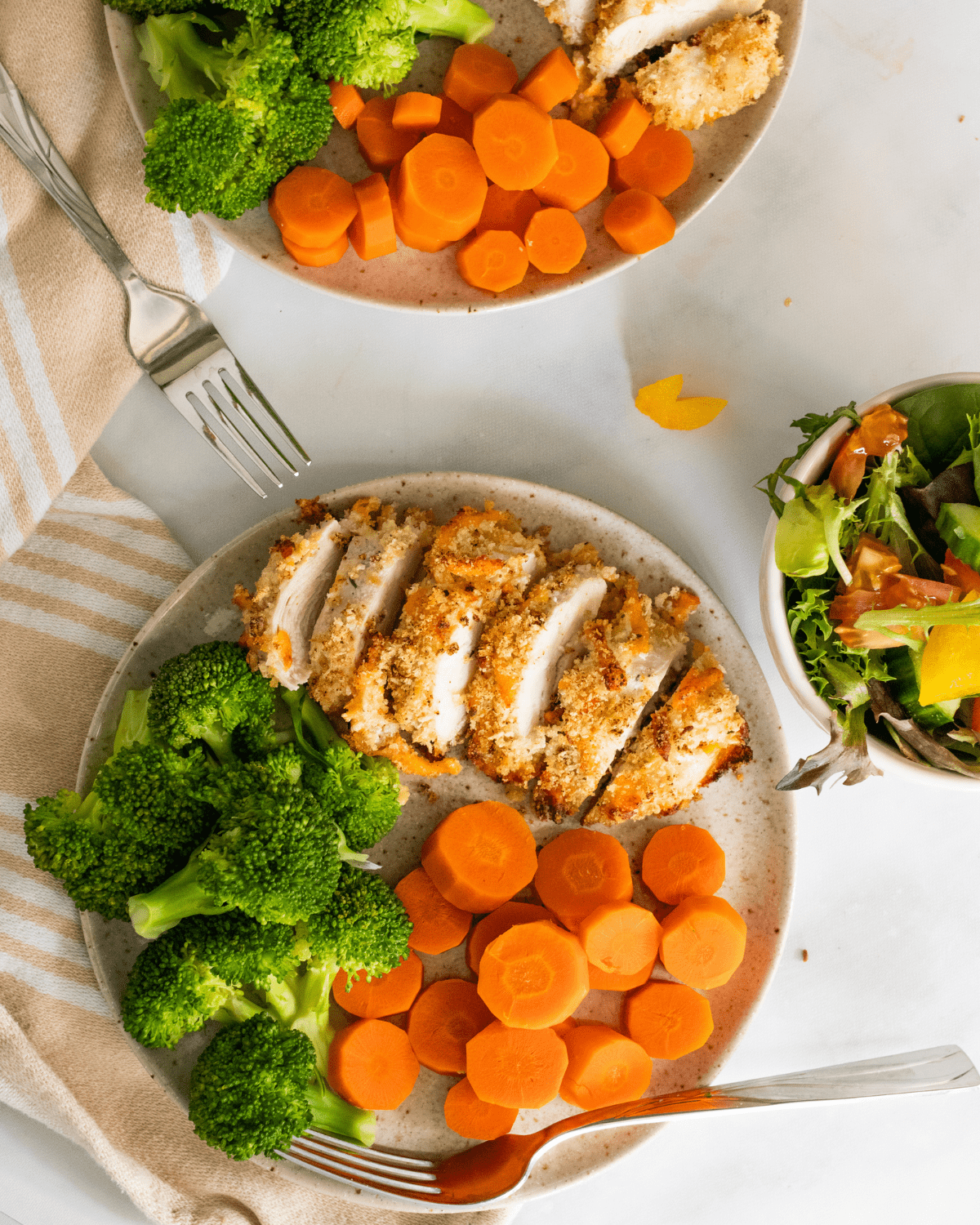 baked ranch chicken on a plate with vegetables and a side salad.