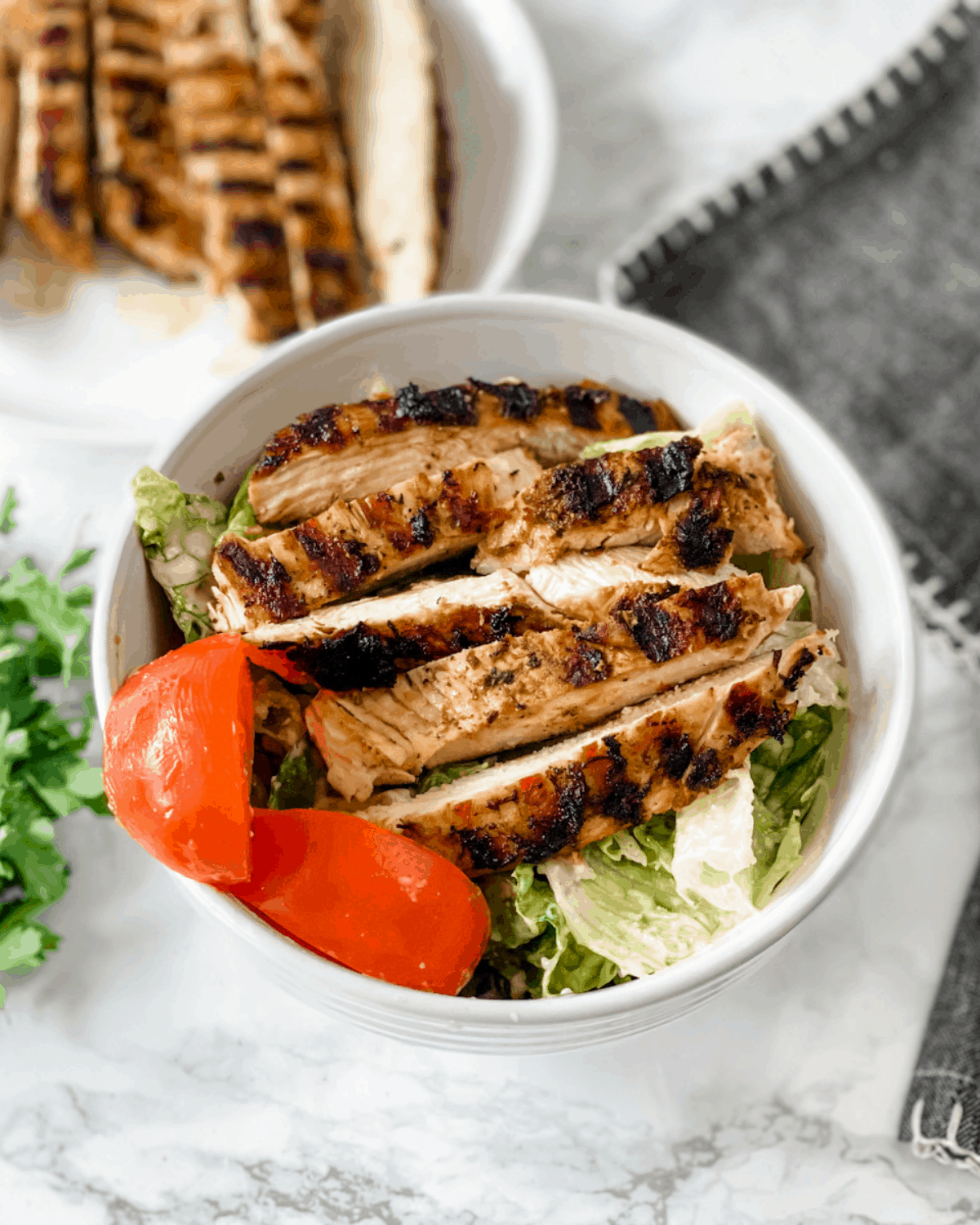 strips of grilled chicken on top of a salad.