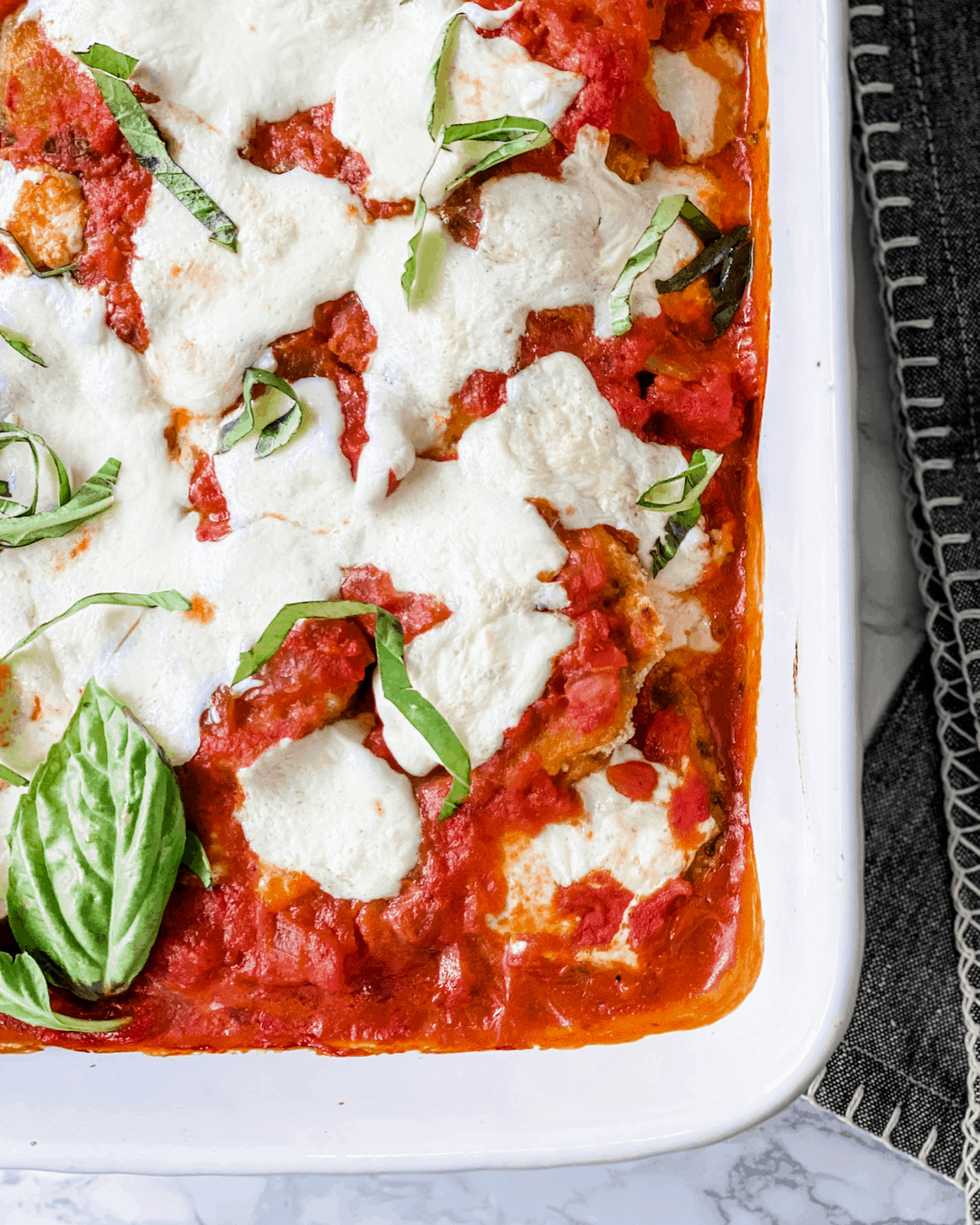 baked eggplant Parmesan cooked in a white ceramic baking dish.