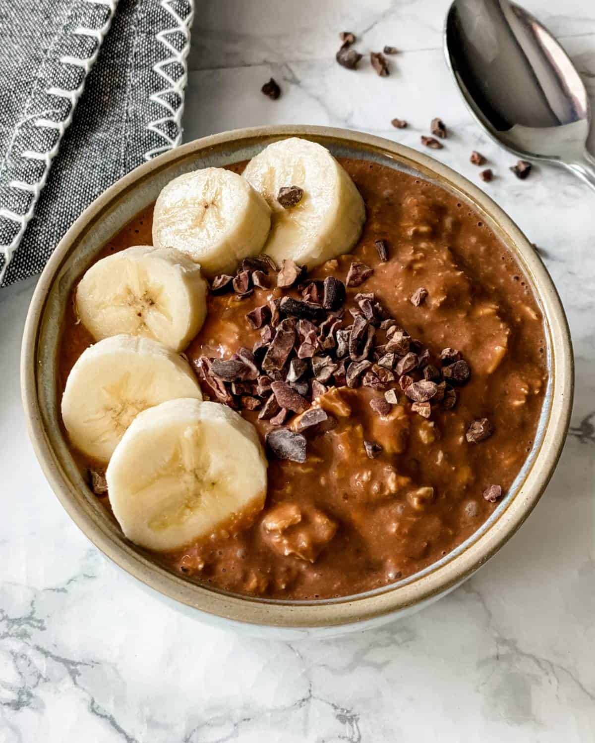 a bowl of chocolate banana overnight oats with sliced banana and cacao nibs on top