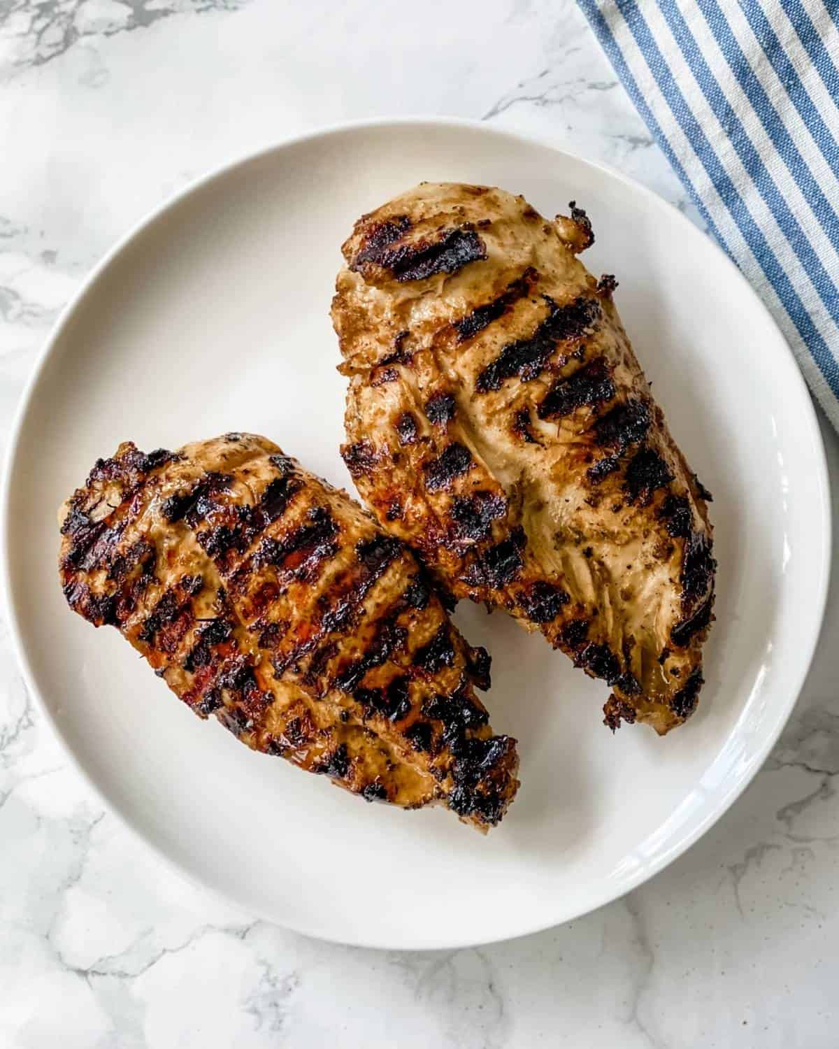 two pieces of grilled chicken breasts on a plate